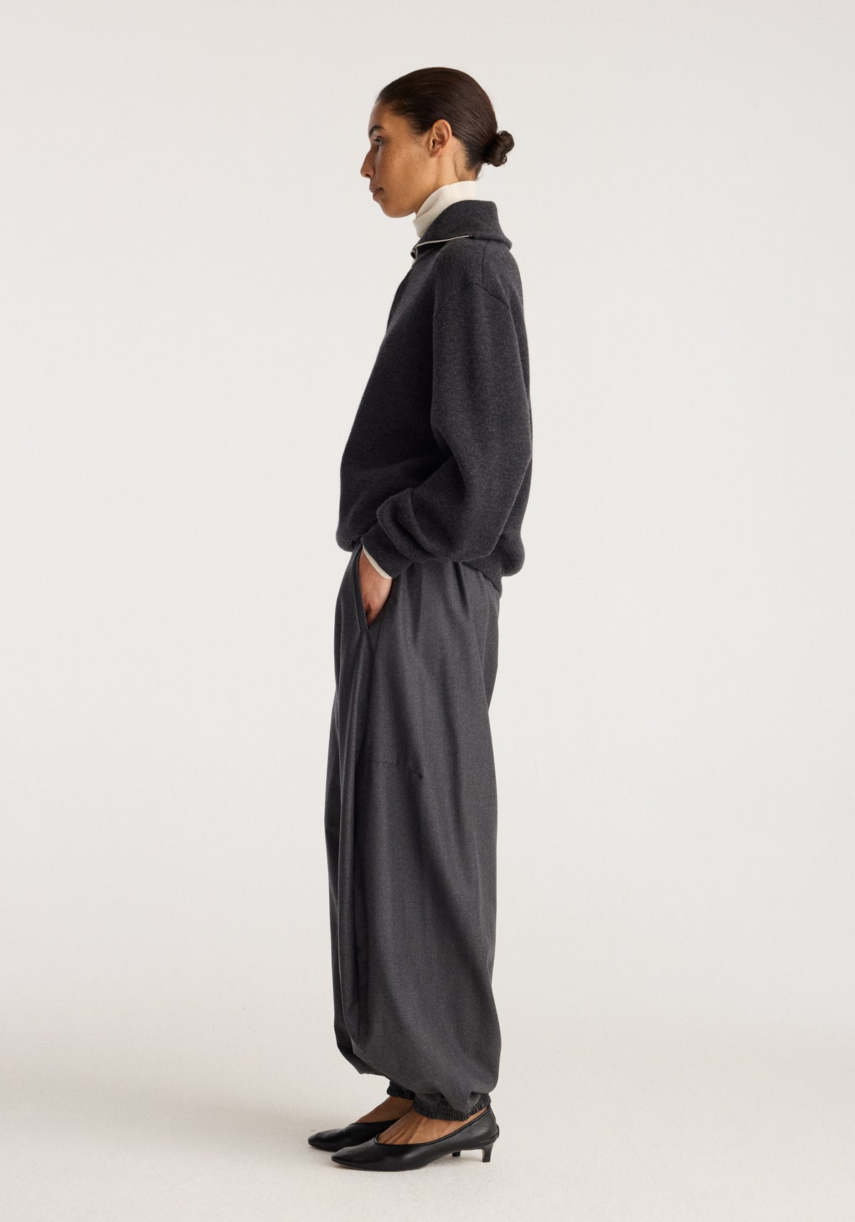 Reversible zipped turtleneck | charcoal shown on a model in side profile with a high collar and relaxed fit paired with dark trousers and heels