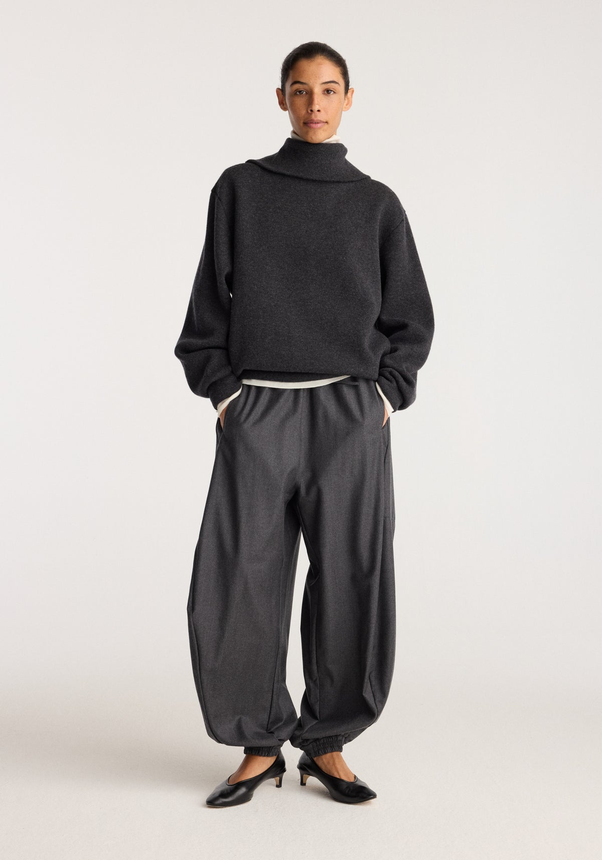 Reversible zipped turtleneck | charcoal worn by a model with relaxed dark trousers and black flats against a neutral studio background