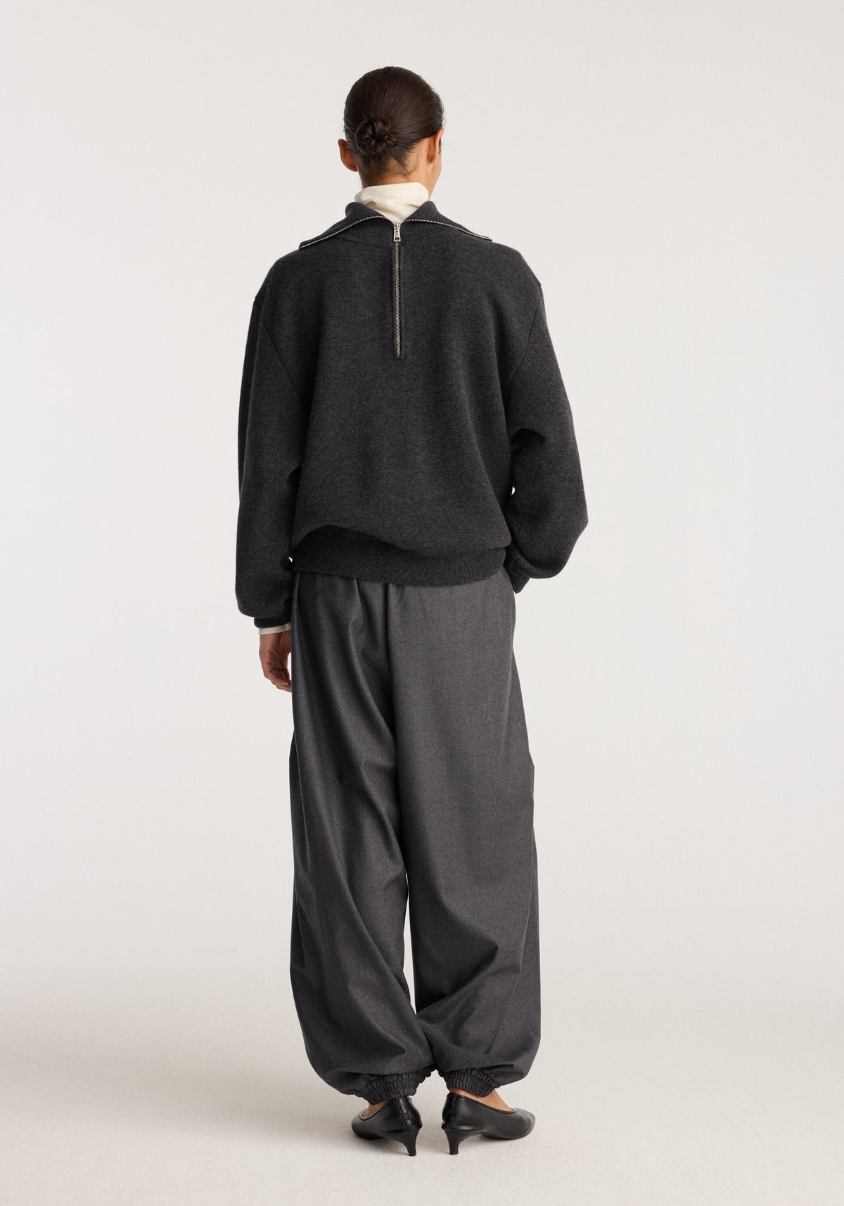 Reversible zipped turtleneck | charcoal shown from the back on a model with a high collar and rear zip, styled with loose charcoal trousers