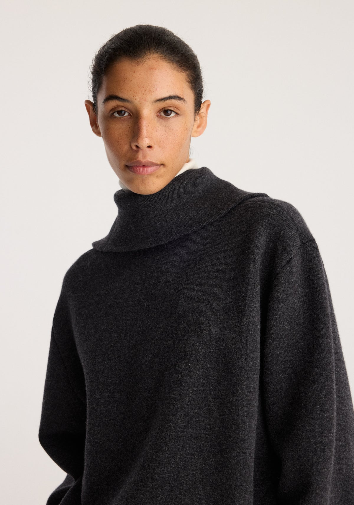 Reversible zipped turtleneck | charcoal worn by a model in a studio portrait with a high neck and relaxed long sleeves