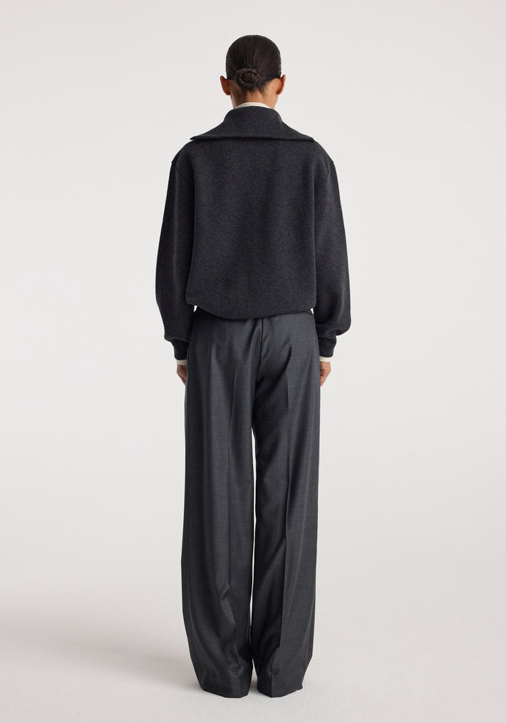 Back view of a person wearing a charcoal Two-way zipped turtleneck with long sleeves paired with loose dark gray trousers against a plain white background.
