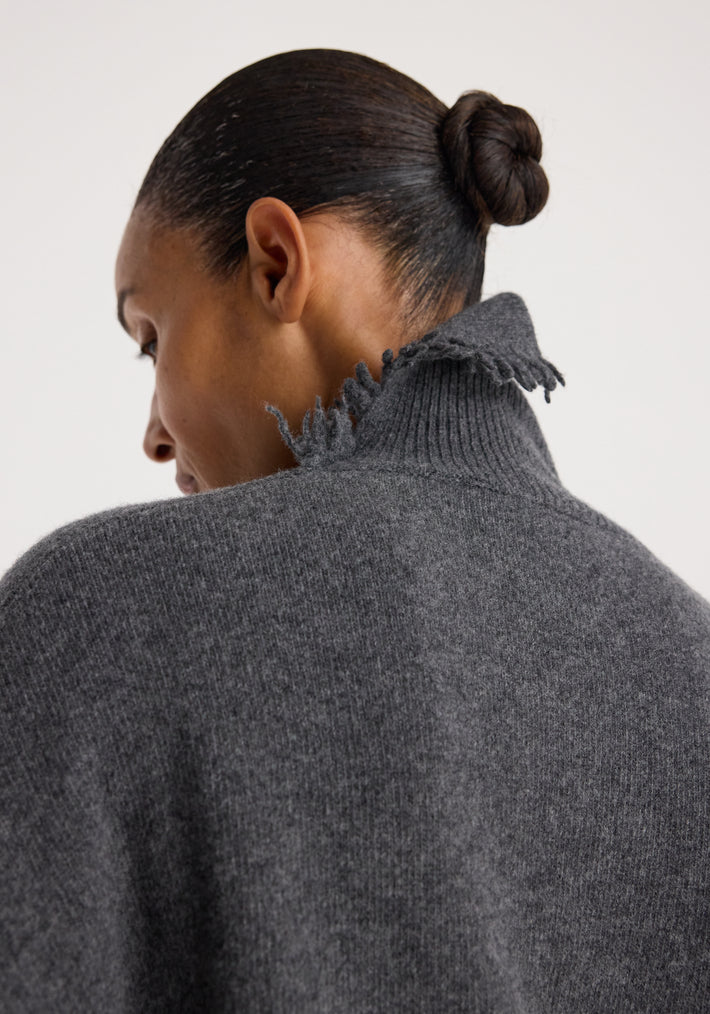 Close-up back view of a person wearing a Turtleneck with raw details | dark grey melange, showcasing the textured fabric and frayed high collar.
