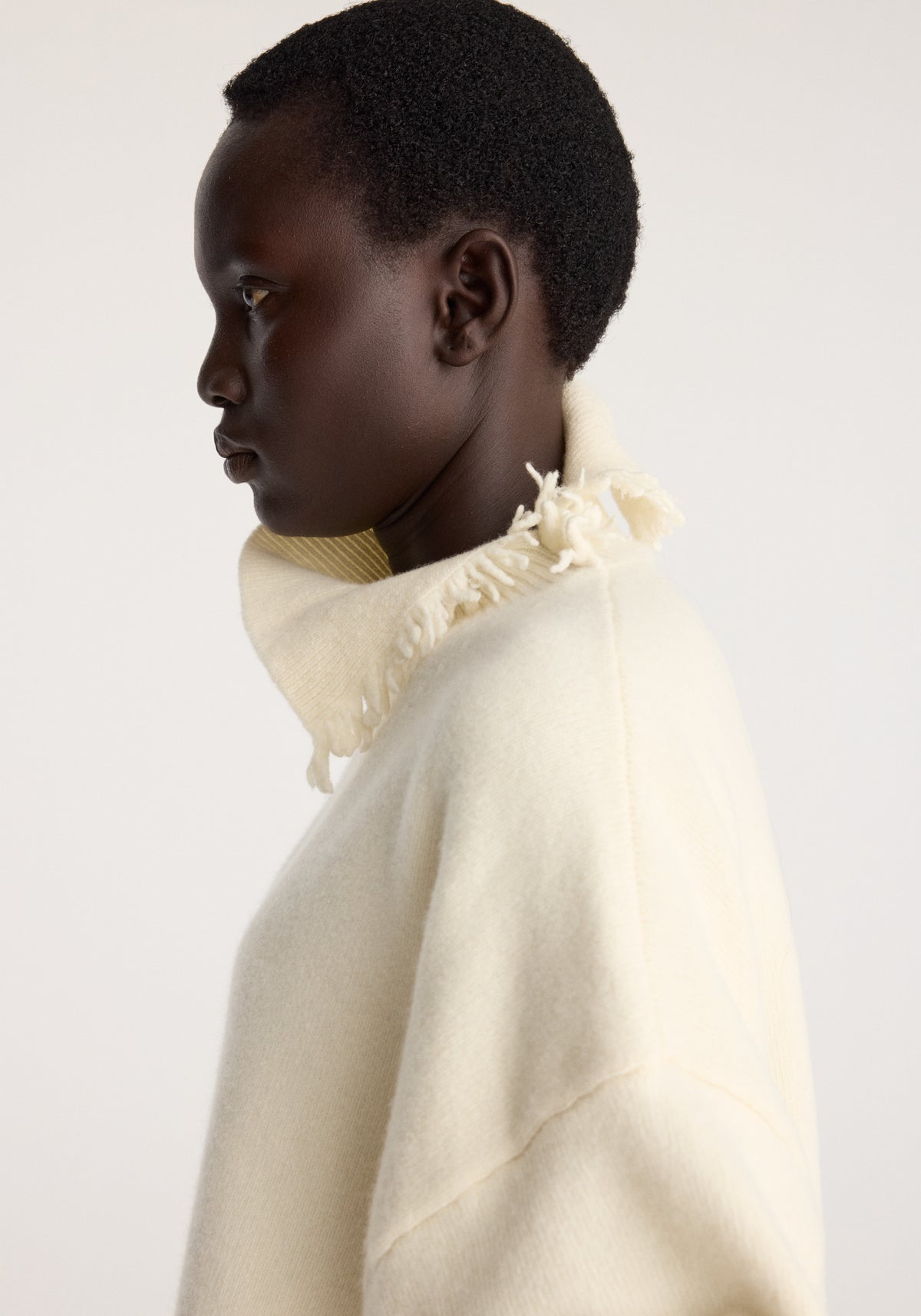 Turtleneck with raw details | off white worn by a model in side profile with a raw frayed neckline and relaxed oversized fit