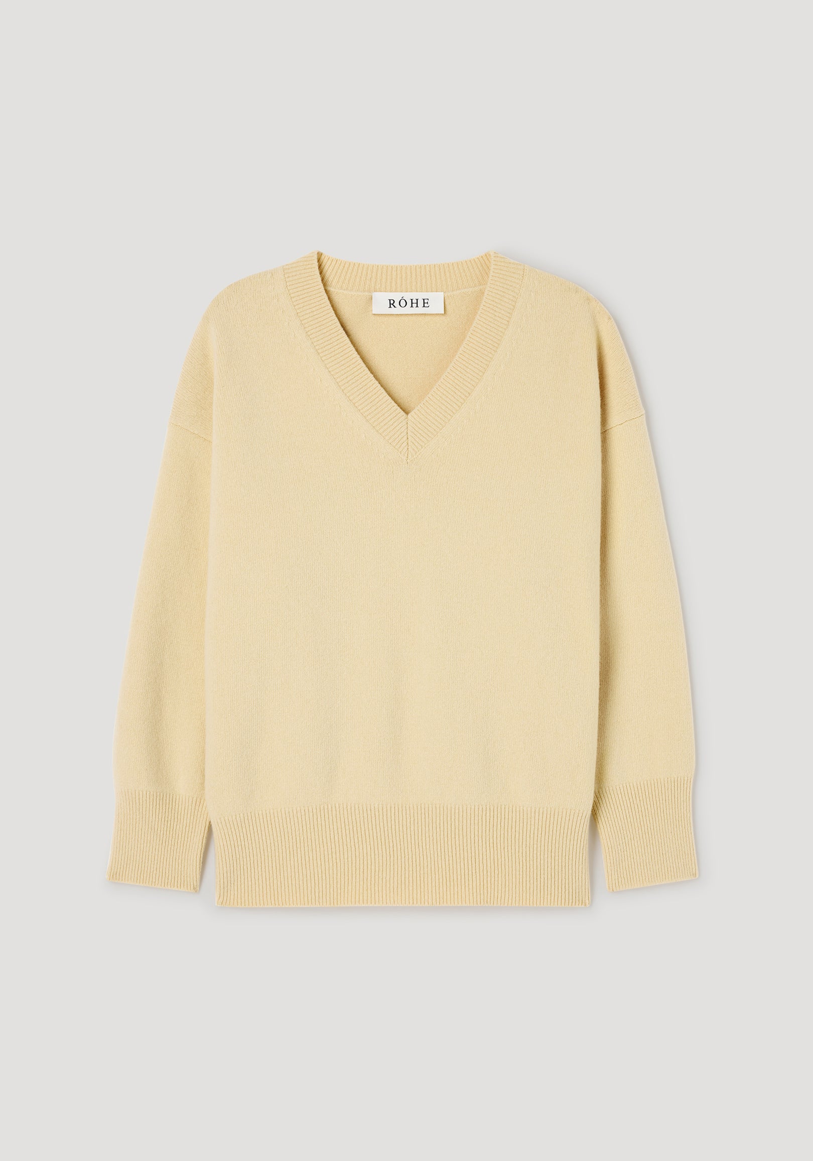 Classic v-neck jumper | butter in a soft light yellow shade with long sleeves, ribbed cuffs, hem, and neckline, displayed on a plain light gray background.