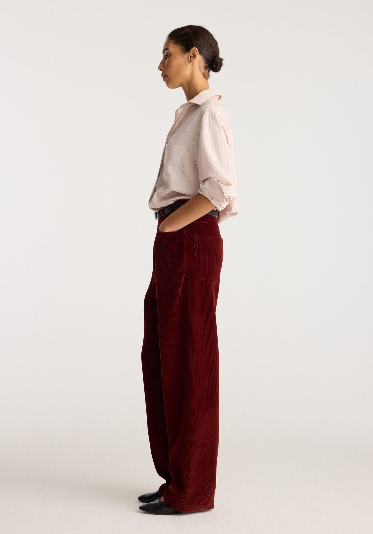 Bruun - Signature baggy corduroy trousers | wine shown on a model in profile with a relaxed fit and wide legs styled with a pale pink rolled sleeve shirt