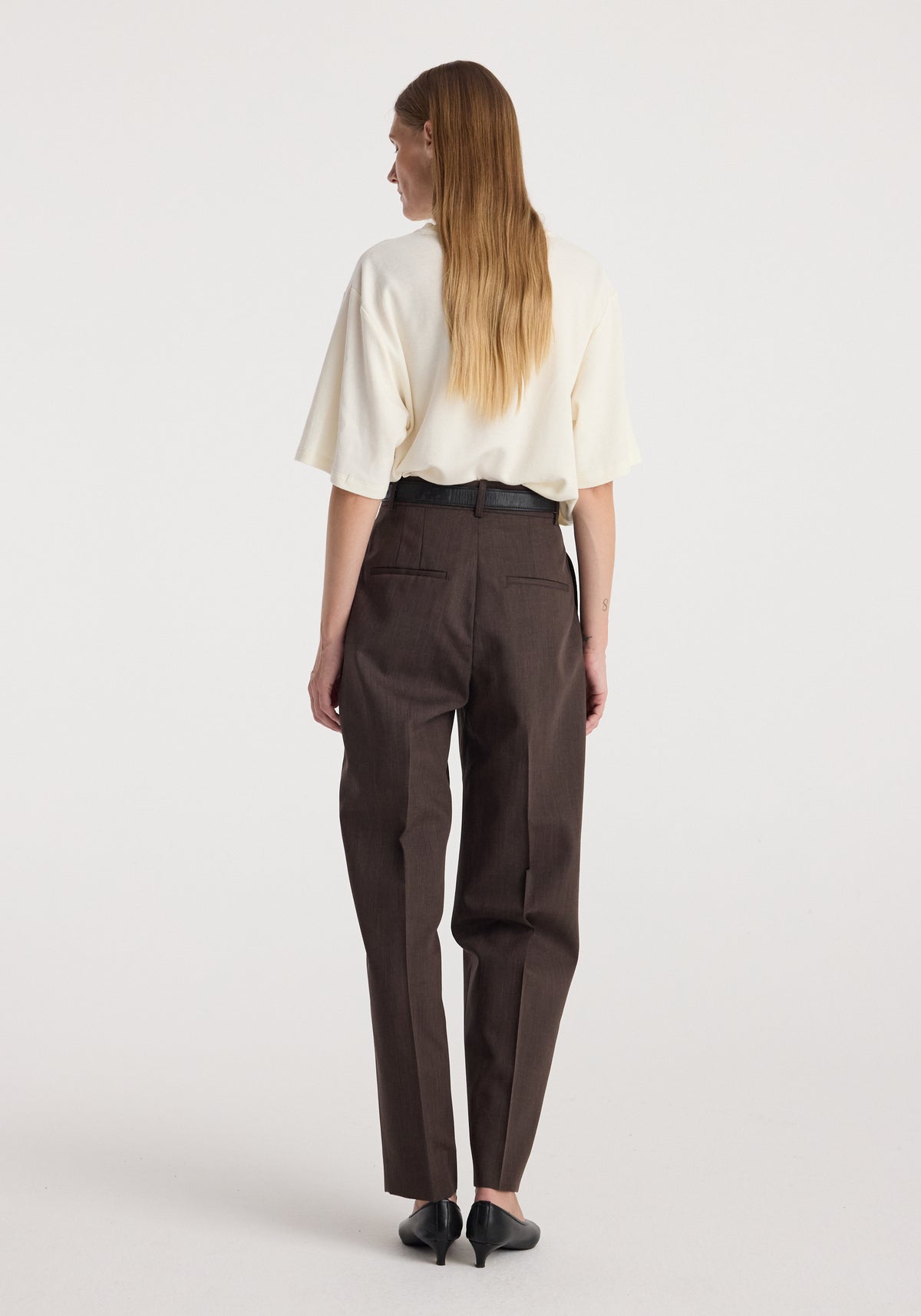 Daria - Single pleat straight leg trousers | dark brown, shown from the back on a model wearing a cream top and black heels