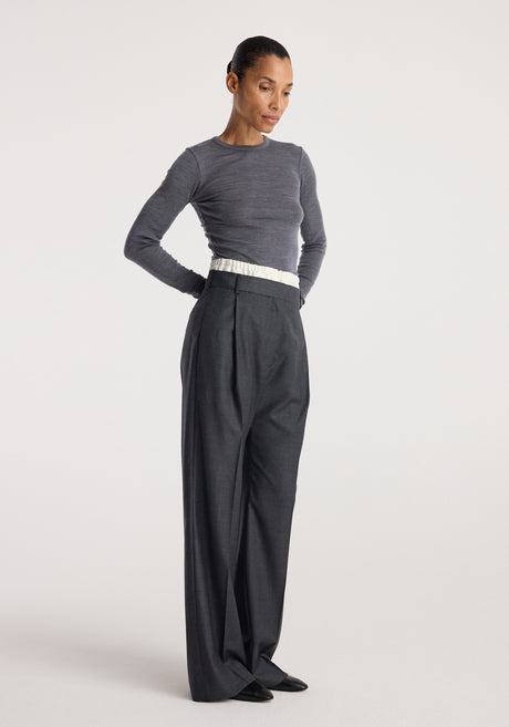 Woman wearing Boxer detailed trousers | dark grey melange with a high waist and wide-leg cut paired with a fitted long-sleeve grey top against a plain background.