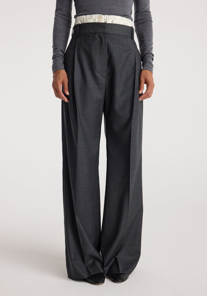 Front view of a person wearing Boxer detailed trousers | dark grey melange with a high waist, pleats, and wide legs paired with a long-sleeve fitted top.