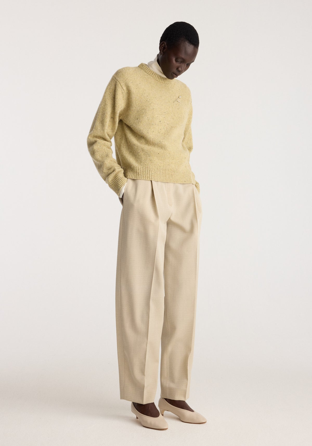 Daria - Single pleat straight leg trousers | butter worn by a model with a cream sweater and beige shoes in a studio setting