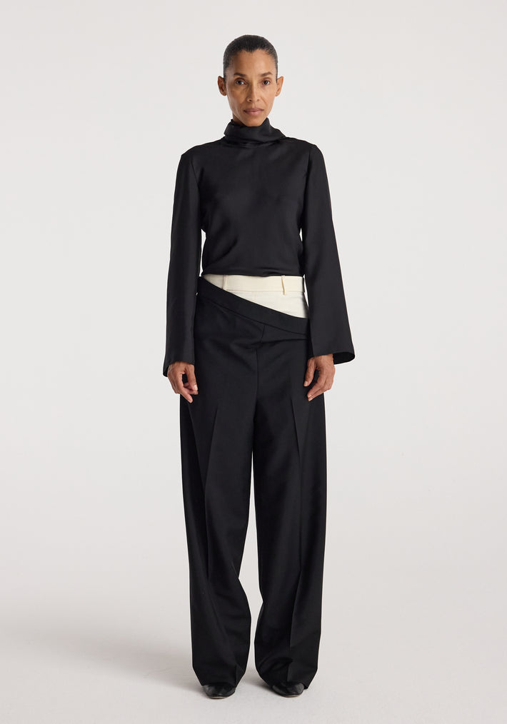 Woman wearing black long-sleeve high-neck top paired with Double waistband trousers | black featuring a unique overlapping waistband design and wide-leg fit.