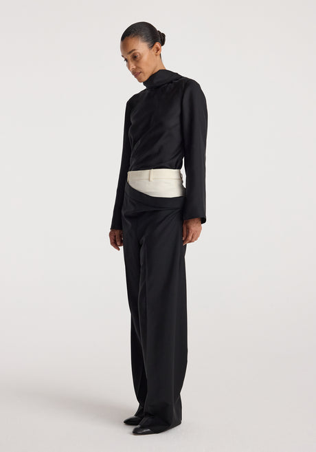 Woman wearing black long-sleeve high-neck top paired with Double waistband trousers | black featuring a unique overlapping waistband design and wide-leg fit.