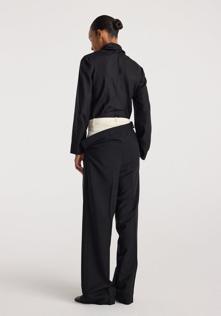 Back view of a person wearing double waistband trousers | black paired with a black long-sleeve top, showcasing the unique layered waistband design.