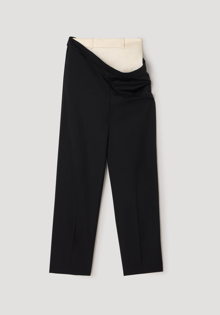 Double waistband trousers | black displayed with an outer black trouser layer partially folded down to reveal an inner beige waistband, laid flat on a neutral background.