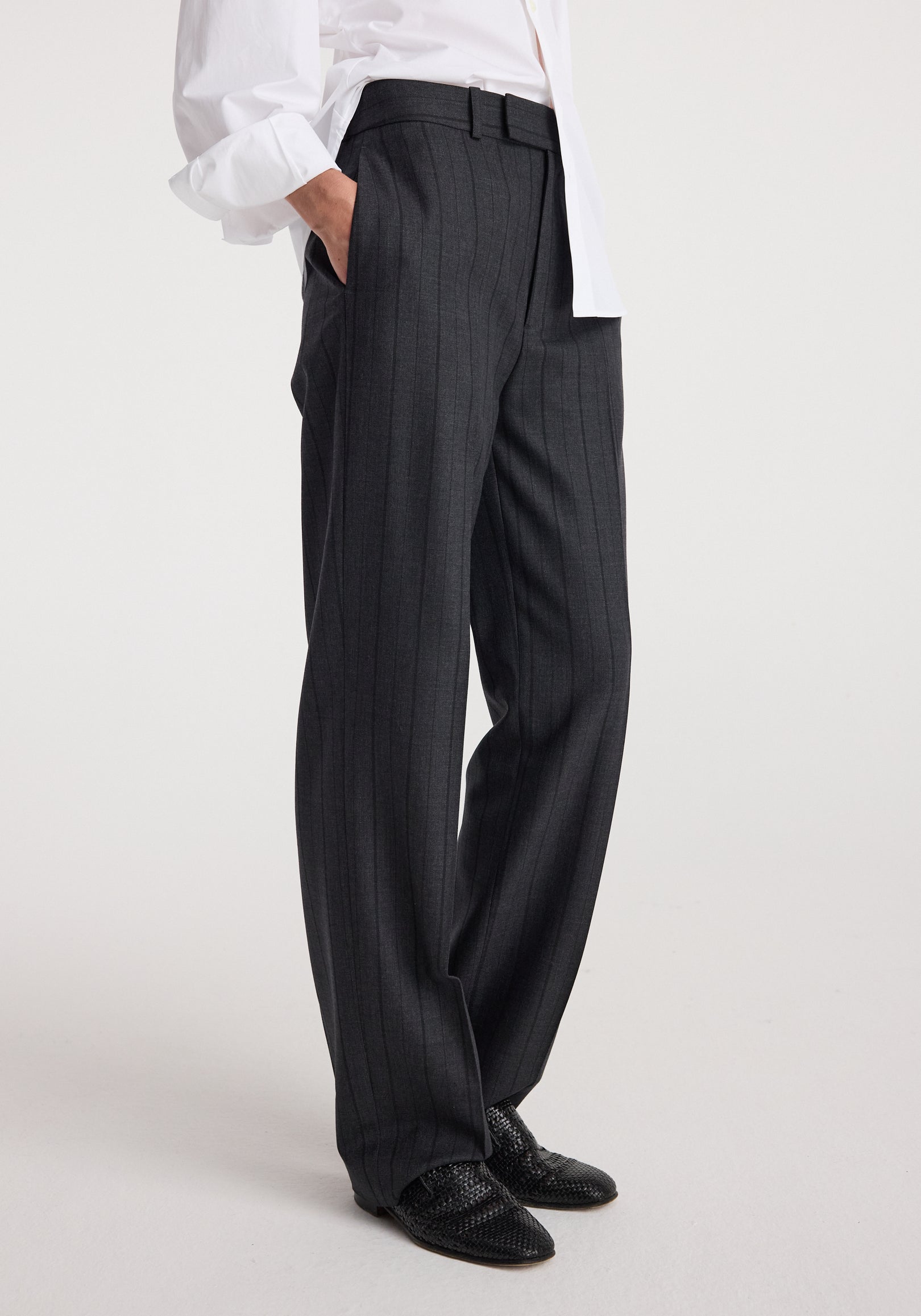 Close-up side view of a person wearing Kee - Straight leg tailored trousers | charcoal stripe paired with black woven shoes and a white shirt.