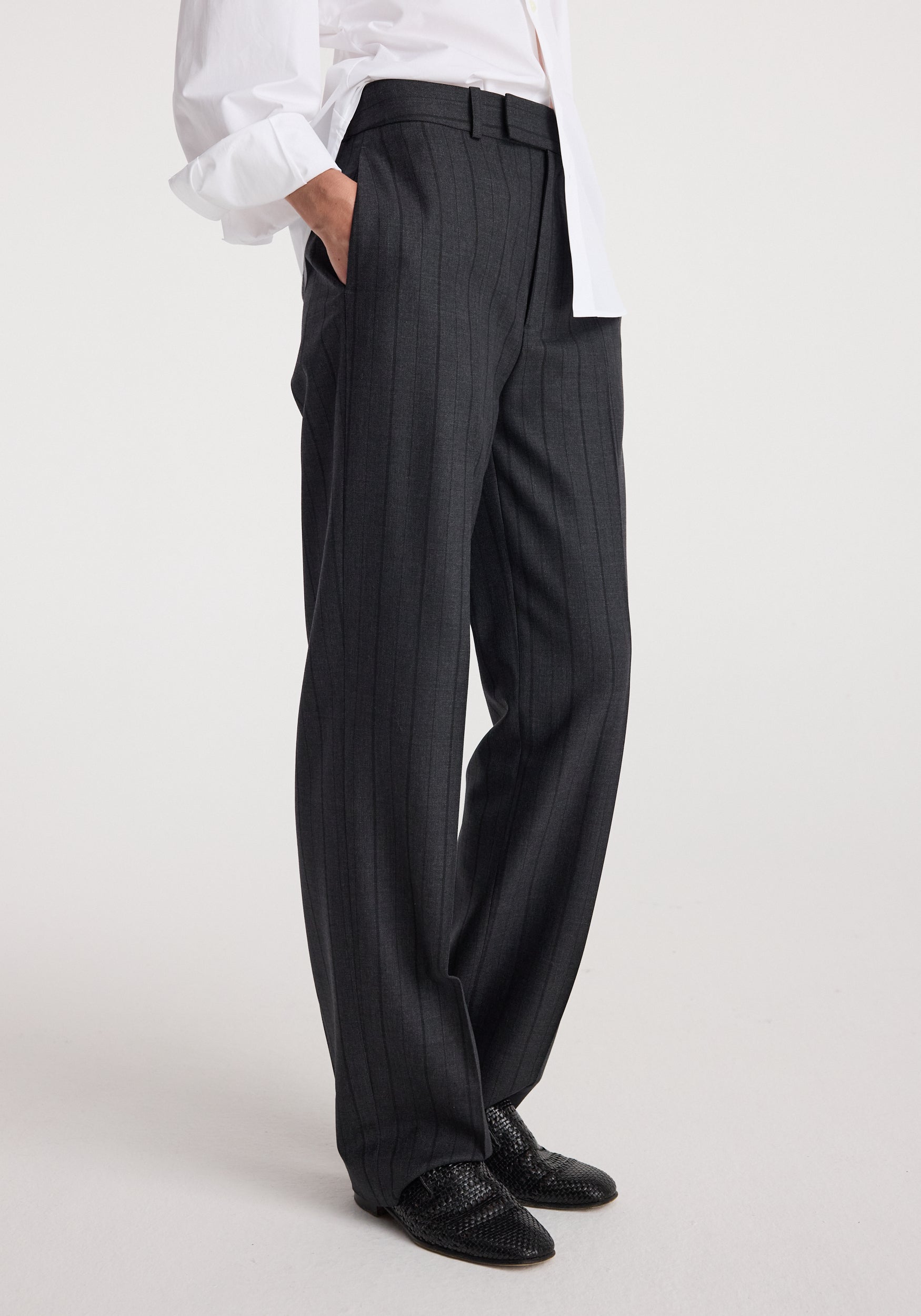 Close-up side view of a person wearing Kee - Straight leg tailored trousers | charcoal stripe paired with black woven shoes and a white shirt.