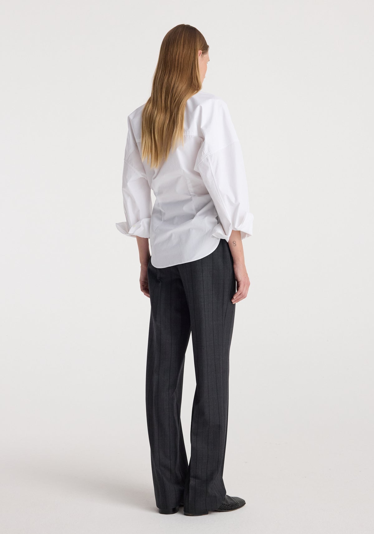 Woman wearing Kee - Straight leg tailored trousers | charcoal stripe, styled with a white long-sleeve shirt, shown from the back against a plain background.