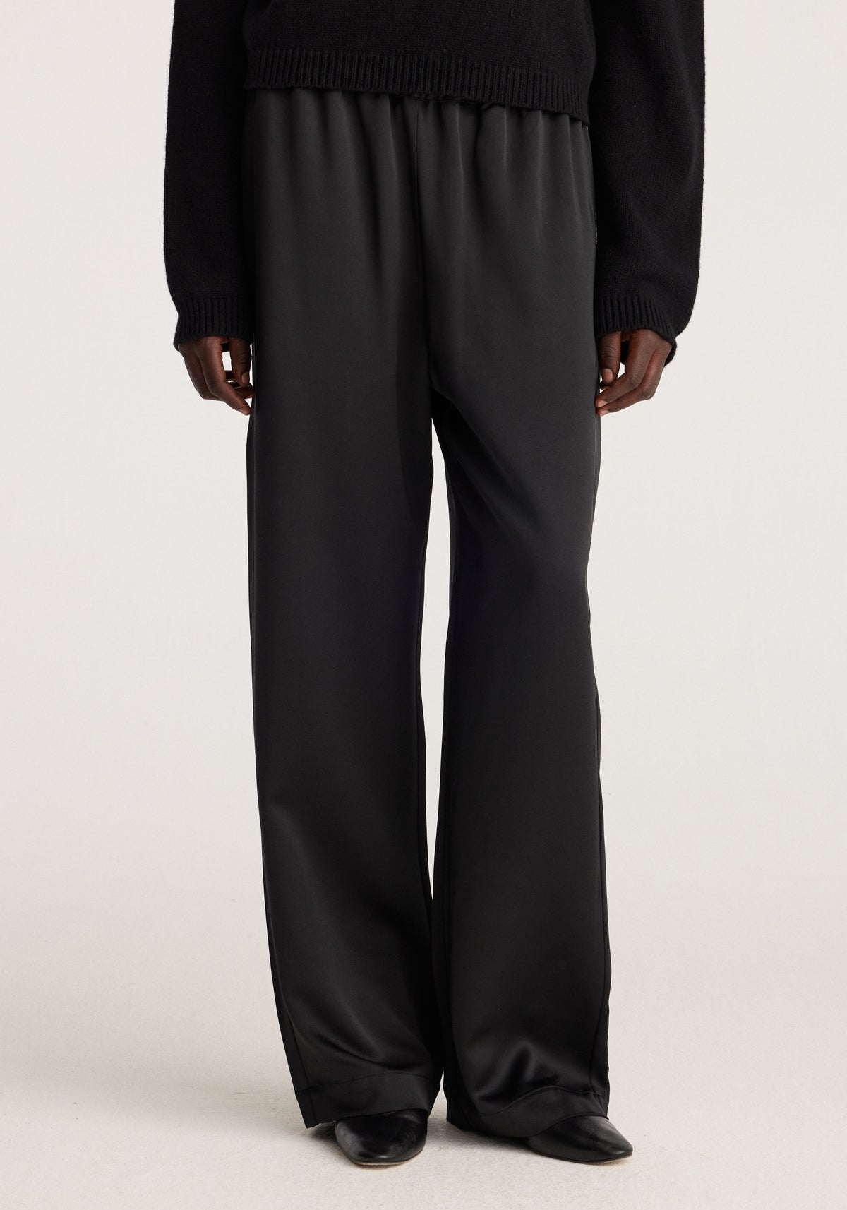 Relaxed fit satin trousers | black shown on a model with a flowing wide leg silhouette and subtle sheen styled with a black knit sweater and loafers