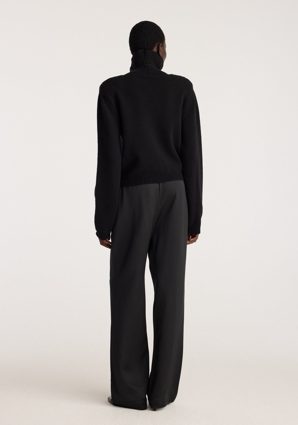 Relaxed fit satin trousers | black shown from the back on a model with a sleek drape and wide relaxed legs