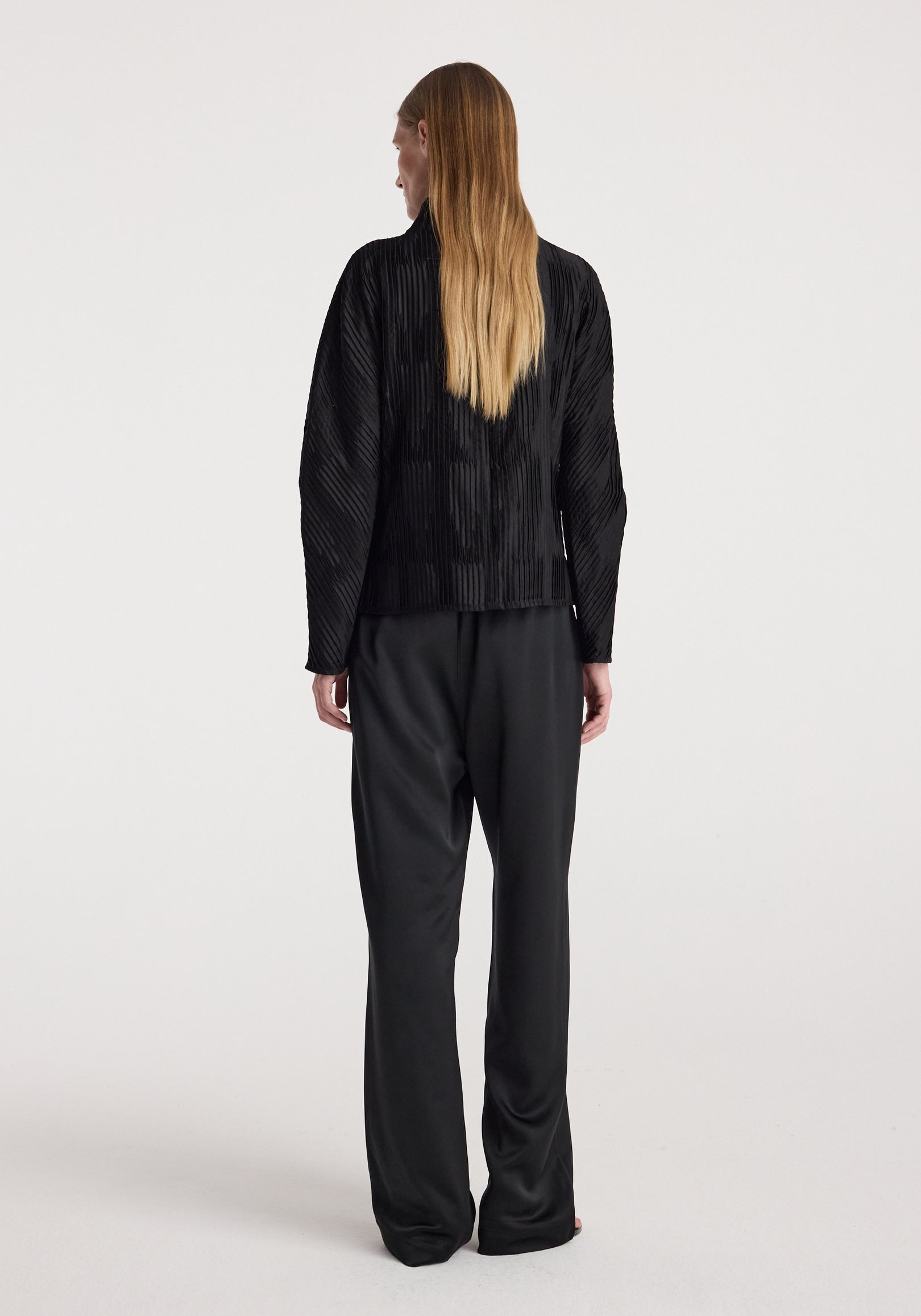 Woman wearing black relaxed fit satin trousers | black, shown from the back with a loose and comfortable silhouette against a plain background.