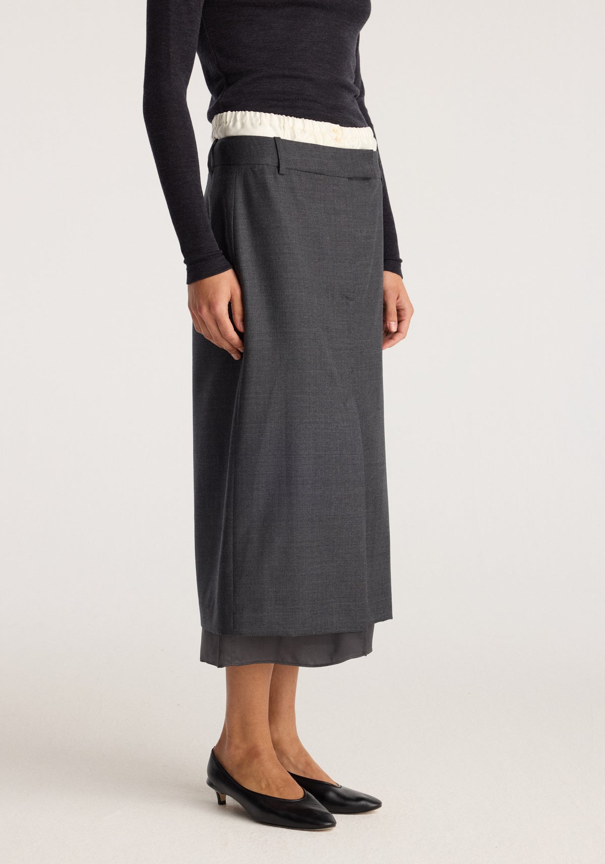Boxer detailed skirt | dark grey melange shown on a model with a straight midi length, layered hem, fitted waistband, and subtle front pleat detail.