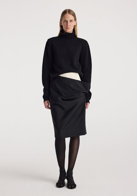 Model wearing a Double waistband skirt | black paired with a black long-sleeve turtleneck sweater, black sheer tights, and black open-toe heels against a plain white background.
