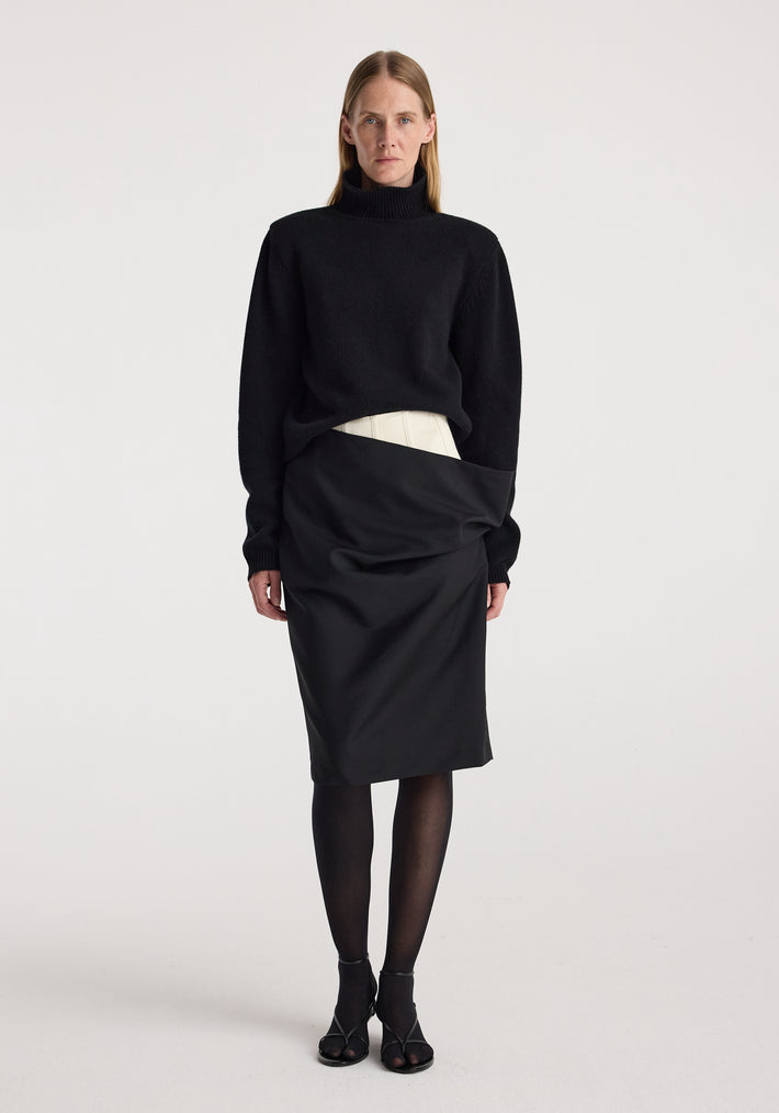 Model wearing a Double waistband skirt | black paired with a black long-sleeve turtleneck sweater, black sheer tights, and black open-toe heels against a plain white background.