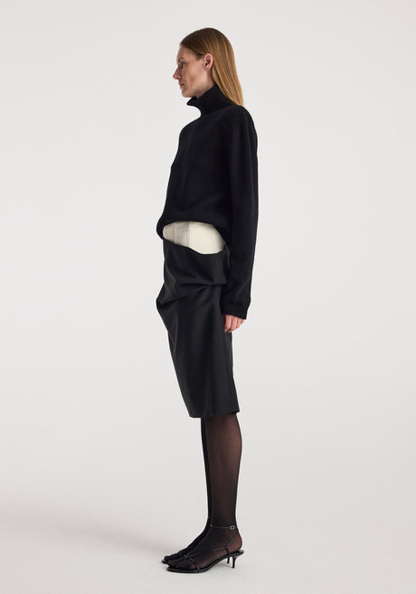 Model wearing a Double waistband skirt | black paired with a black long-sleeve turtleneck sweater, black sheer tights, and black open-toe heels against a plain white background.