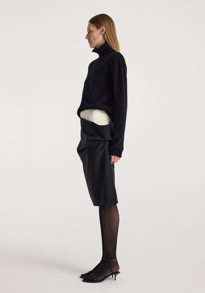 Woman wearing black turtleneck sweater and black sheer tights paired with the Double waistband skirt | black, featuring a unique double waistband design and knee-length fit.