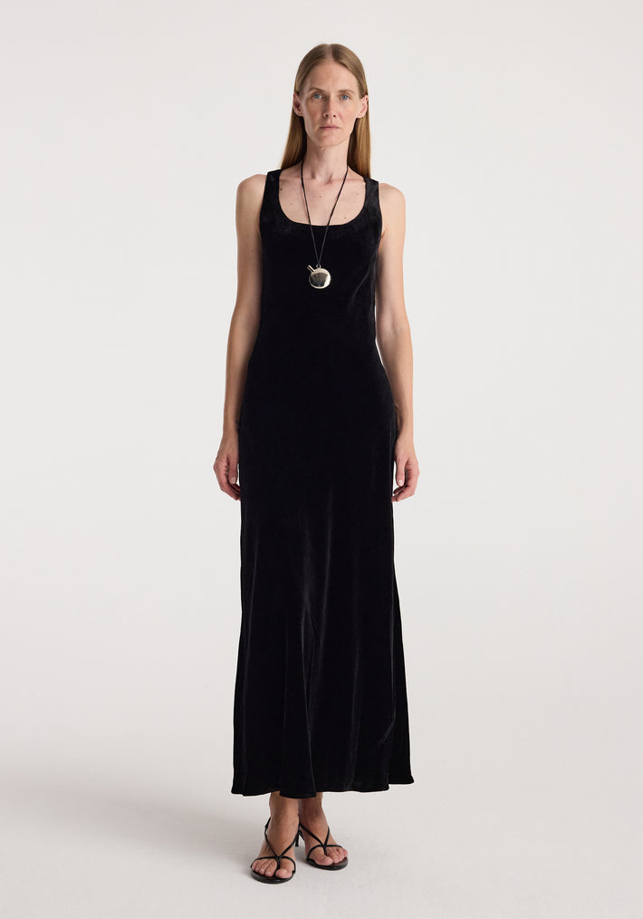 Woman wearing a long black velvet sleeveless dress paired with a Silver perfume bottle necklace | silver pendant hanging from a thin black cord around her neck.