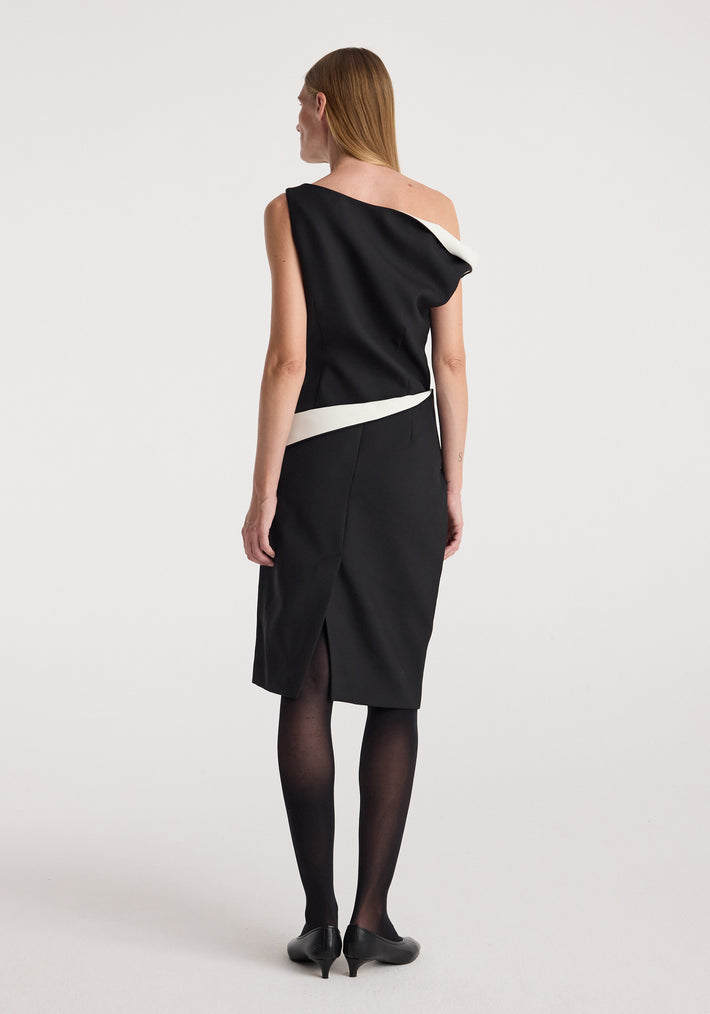 Woman wearing a Sculptural off-shoulder dress | black with a contrasting white accent, standing with her back to the camera against a plain background.