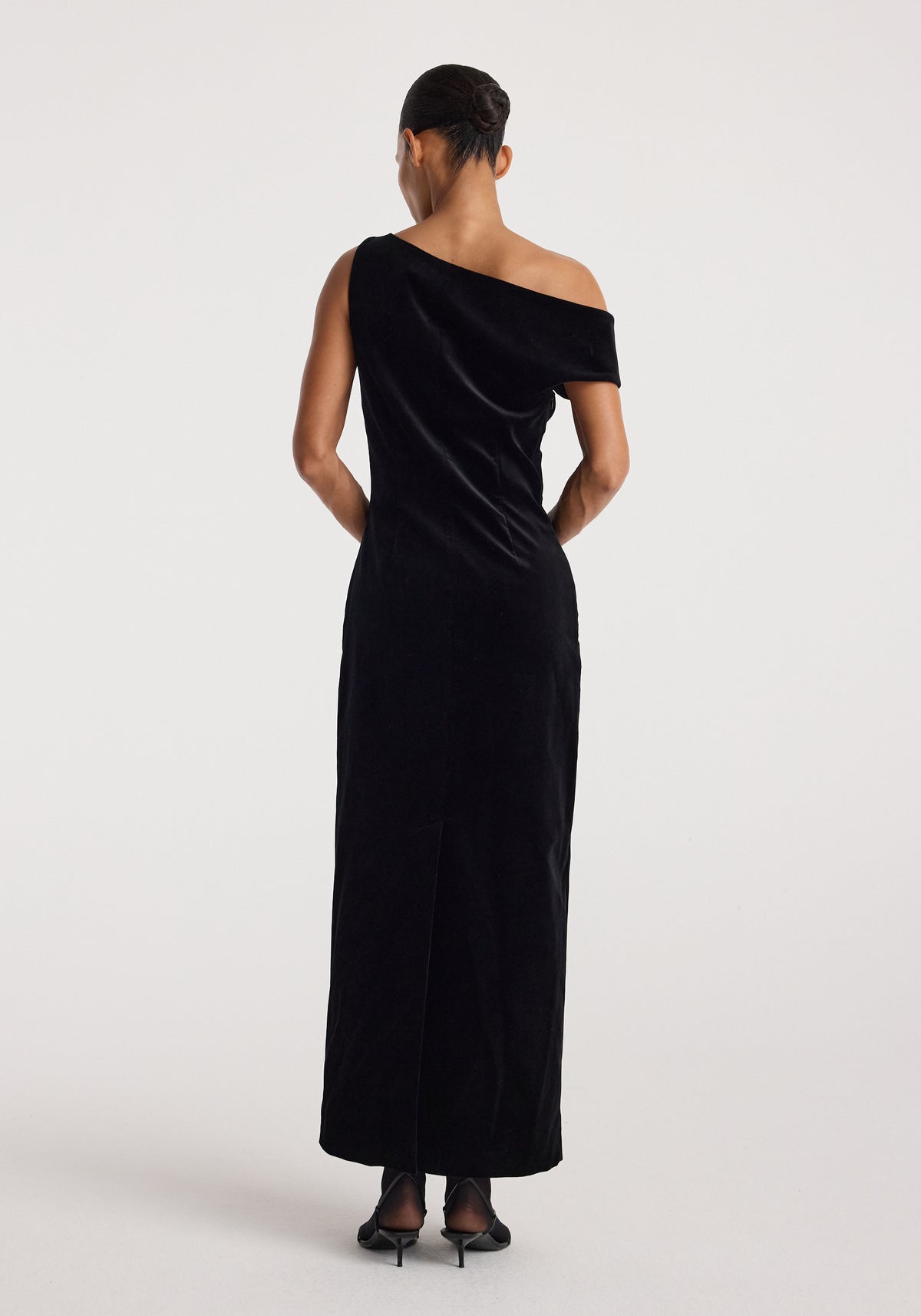 Sculptural off-shoulder velvet gown | black, shown from the back on a model with an elegant draped neckline and floor-length silhouette