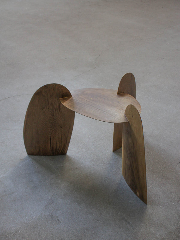 Sculpted Stool | 4673: A handcrafted, interlocking oak stool by Arne Kristian, featuring a minimalist tripod design, displayed on a concrete floor.