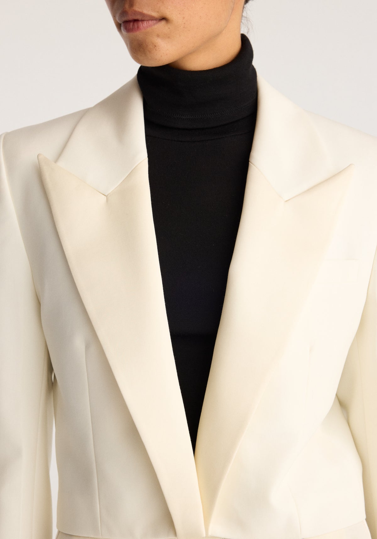 Cropped blazer | off white with a tailored cropped fit, wide lapels and an open front, styled over a black turtleneck top