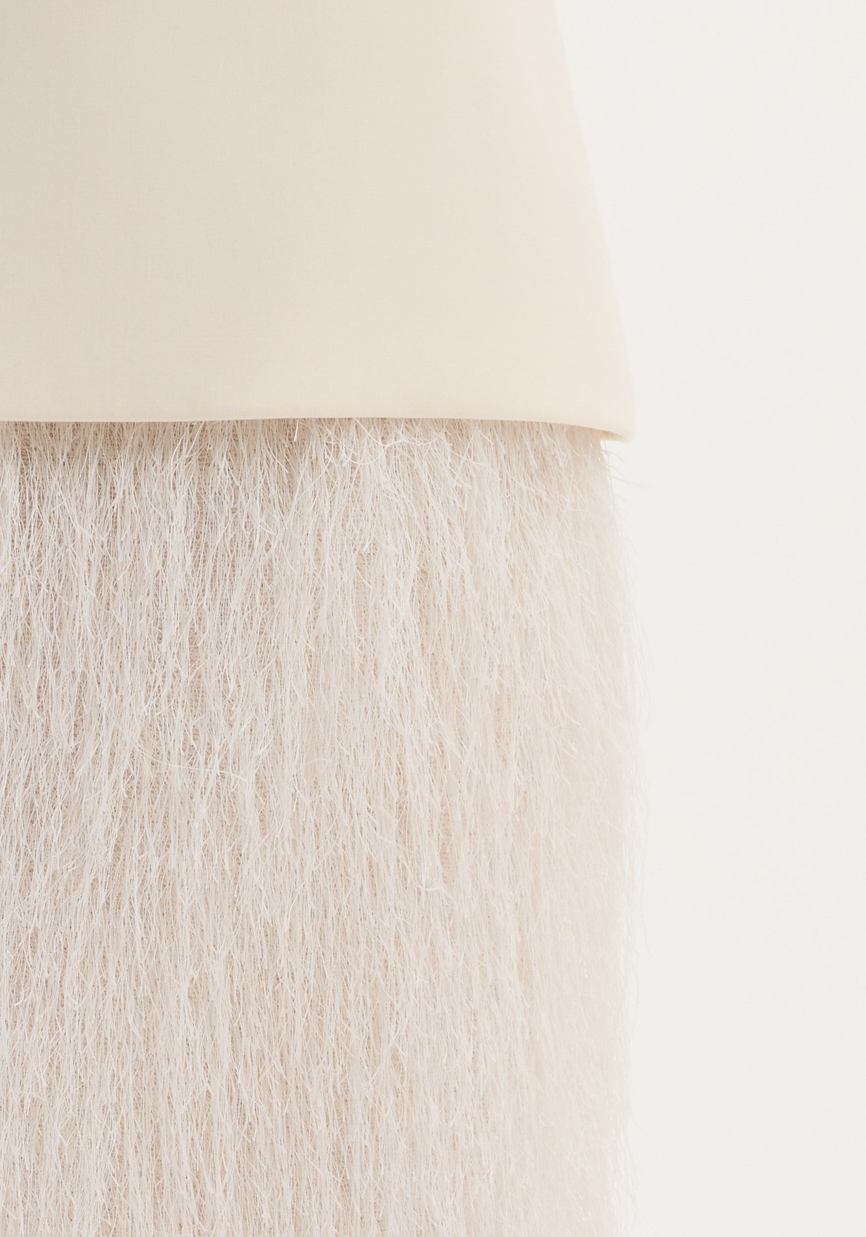 Close-up of the Fringe skirt | ivory, showcasing its smooth handle-like top and tightly packed fringe, highlighting the textured movement and structured wool blend.