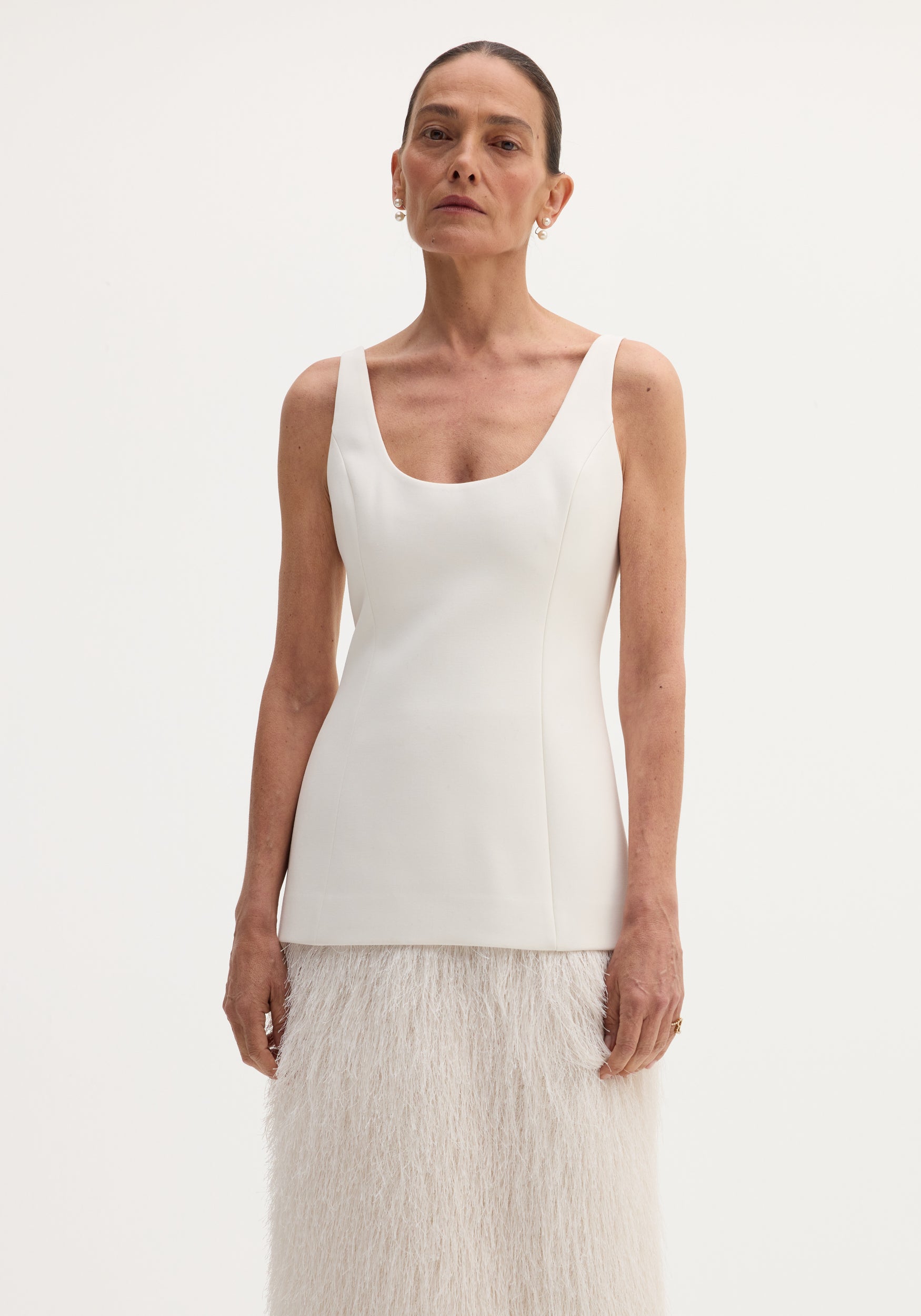 Fringe dress | ivory: A tall woman models a sleeveless, scoop-neck bodice with a long, feather-textured skirt, featuring a back slit for ease of movement.