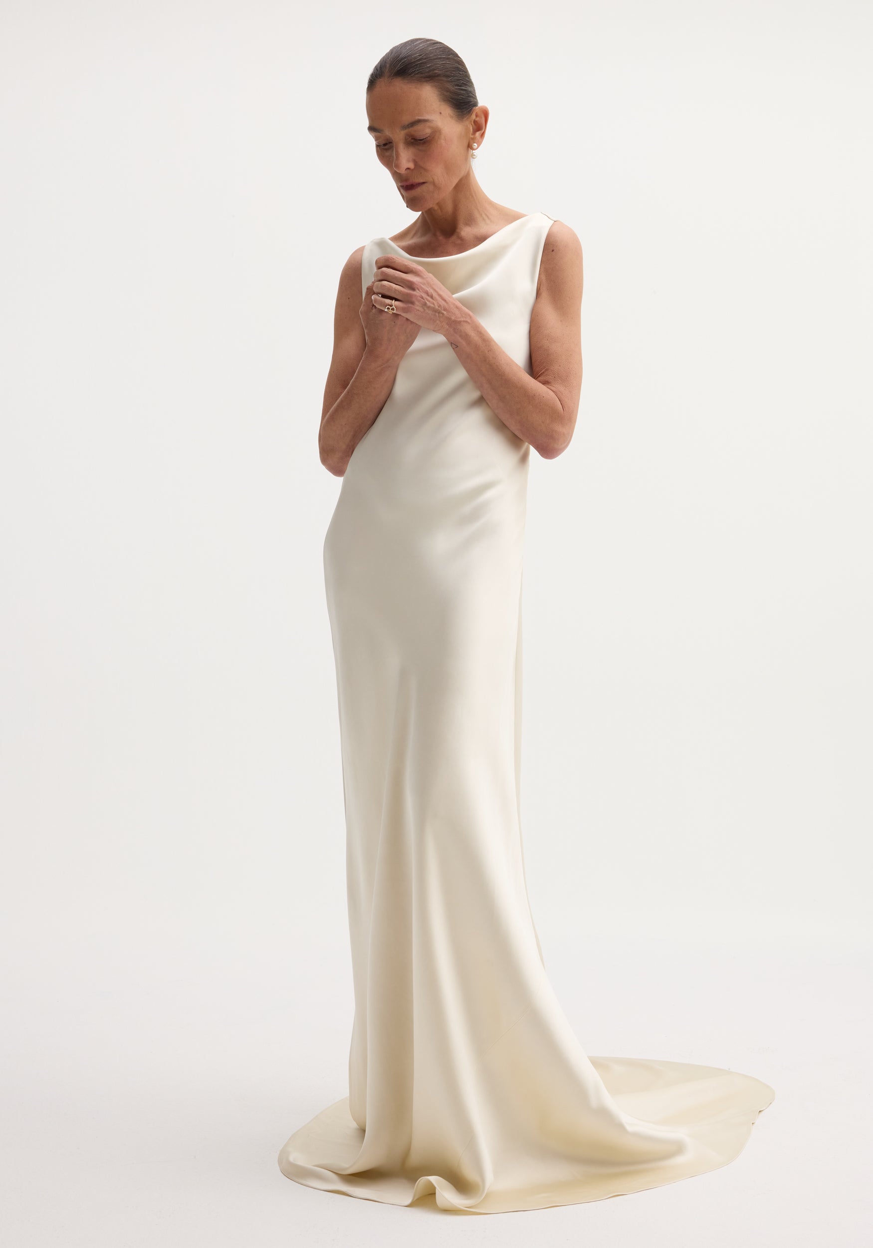 Draped satin dress with train | ivory: A sleeveless, floor-length gown with a bateau neckline, bias-cut for elegant drape, featuring a smooth column silhouette and elegant train.