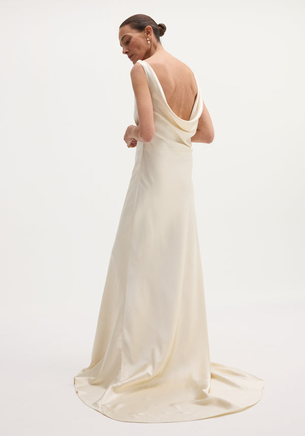 Woman in ivory Draped Satin Dress with Train, featuring a sleeveless design, cowl back, and a pooling train, accessorized with pearl earrings.