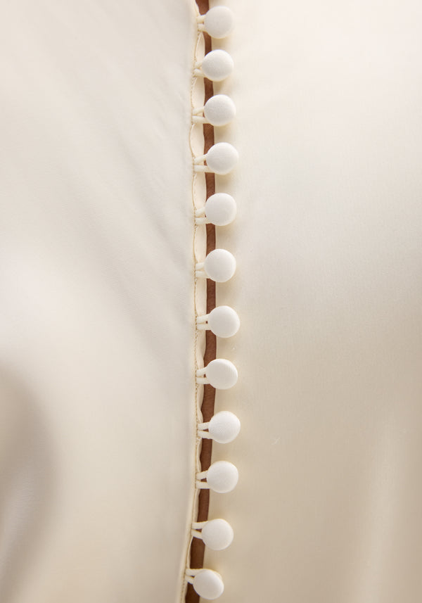 Close-up of Satin button down dress with train in ivory, showcasing fabric-covered buttons along the seam and delicate bias draping from the high neck.