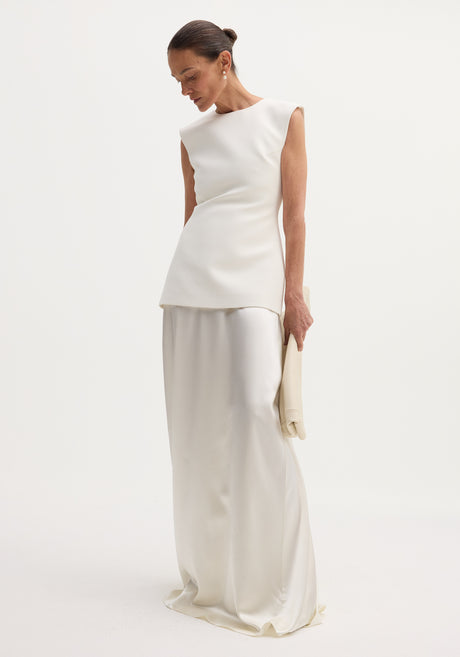 Model in Classic signature dress with satin silk skirt | ivory, featuring a structured bodice, open back, and flowing long skirt, accessorized with an oversized clutch.