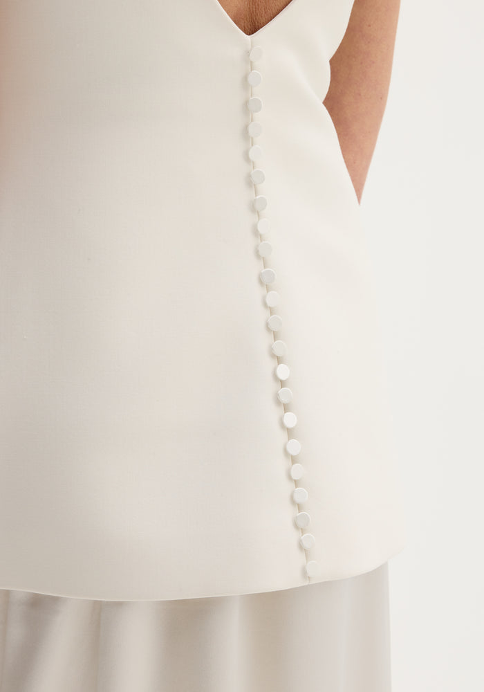 Woman wearing Classic signature dress with satin silk skirt | ivory, featuring a fitted wool-blend bodice, open back, and diagonal button detail.