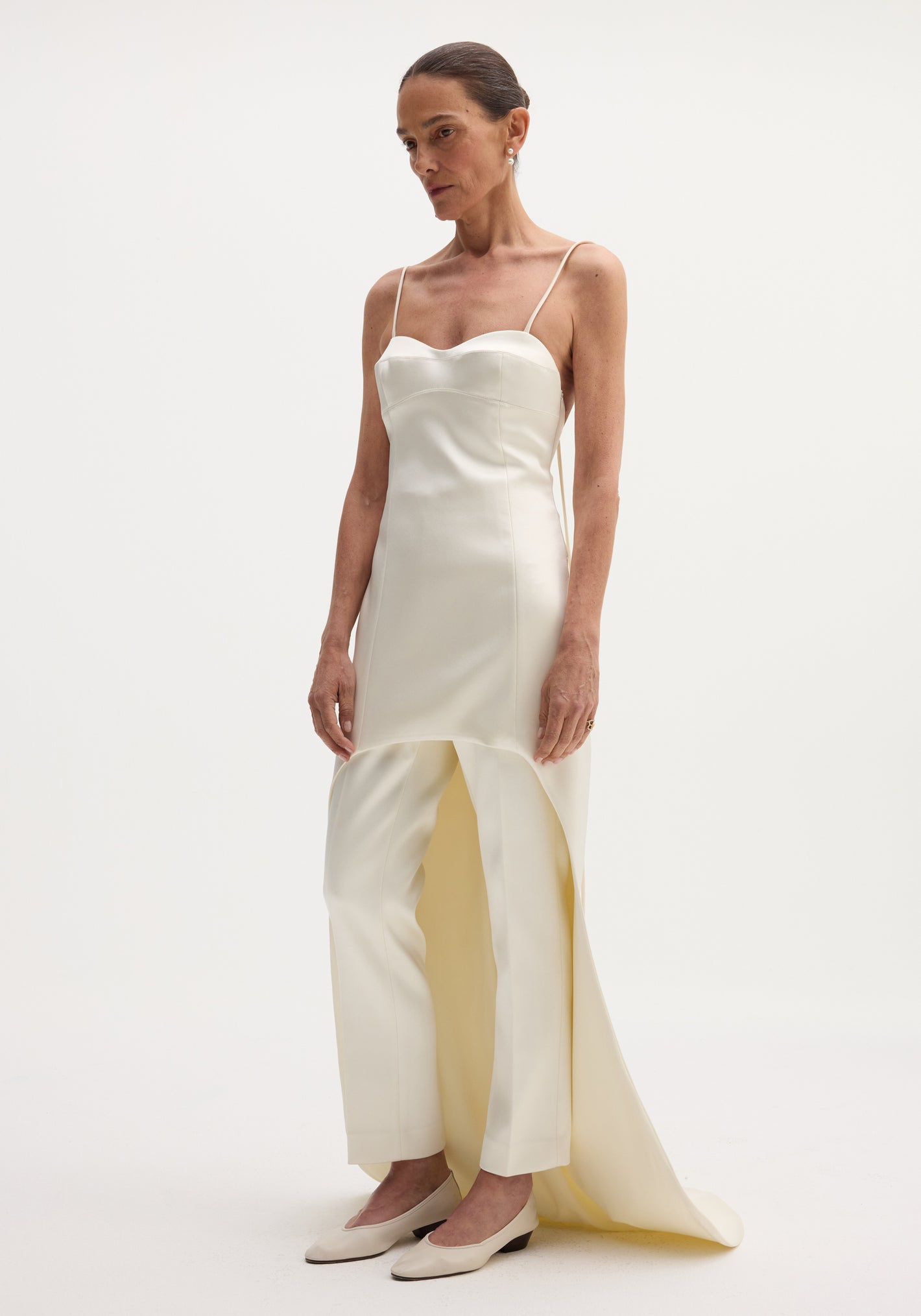 Model wearing a Satin bustier dress with train, featuring a sweetheart neckline and paired with matching wide-leg trousers and ivory pumps.