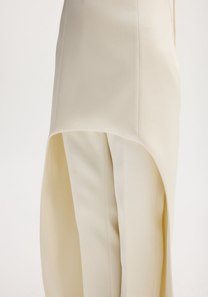 Ivory satin bustier dress with an elegant train, featuring asymmetrical draping over tailored trousers, showcasing bustier stitching and adjustable straps.