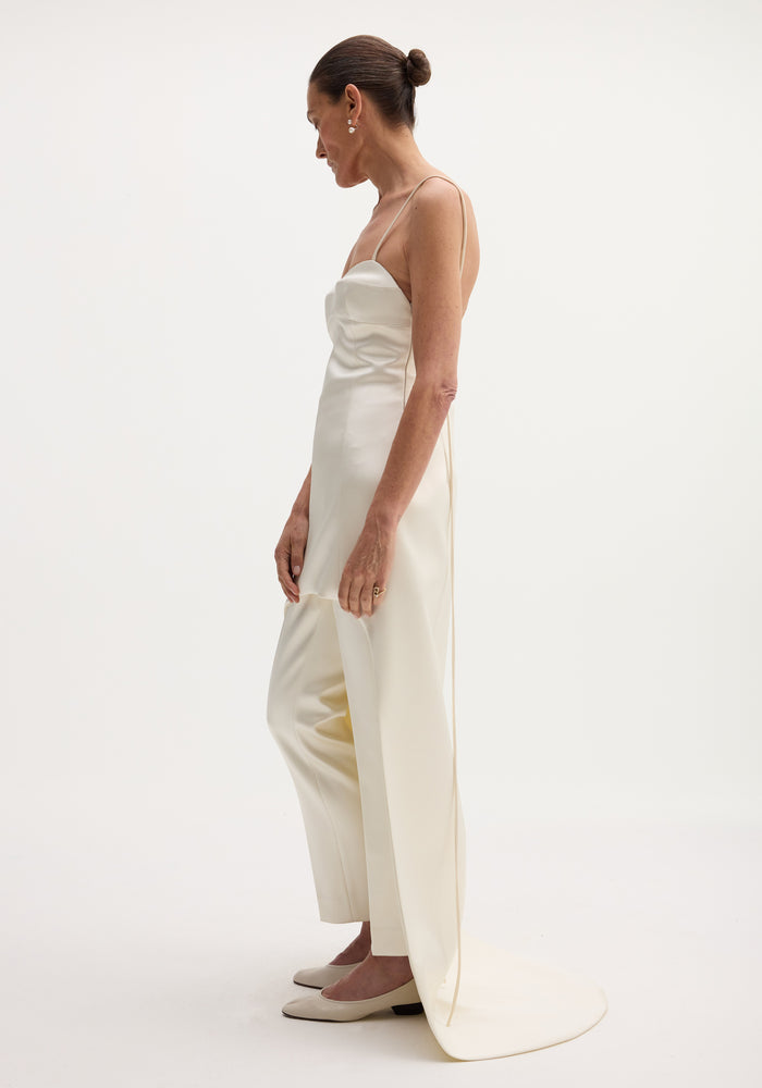 Woman in profile wearing a Satin bustier dress with train, styled with matching trousers, low bun, minimal jewelry, showcasing a modern, fluid look.
