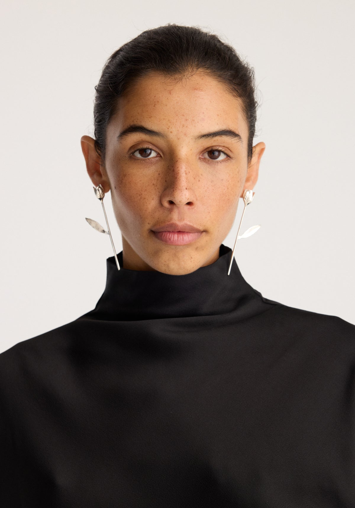 Tulip silver earrings (pair) | silver worn by a model, featuring delicate botanical drop shapes on thin silver hooks against a black top