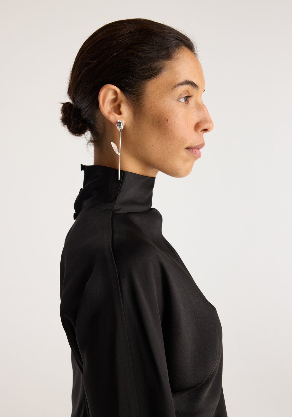 Tulip silver earrings (pair) | silver worn by a woman in side profile, featuring a delicate long drop design with a small tulip shaped detail.