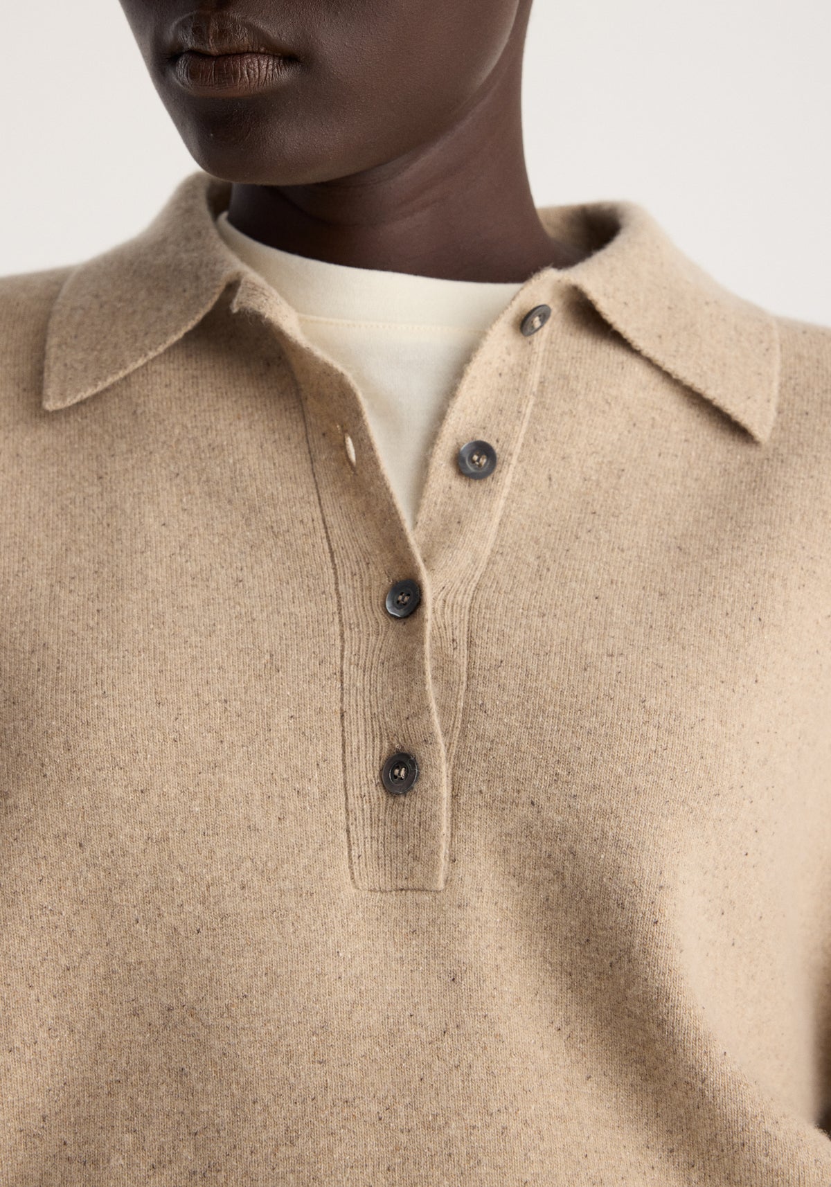 Wool cashmere polo | stone melange shown in close-up with a soft beige knit texture pointed collar and dark buttons on the placket