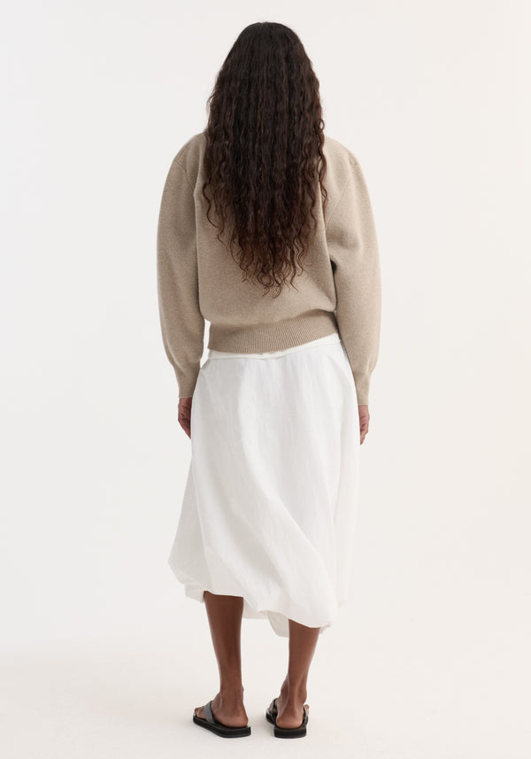 Back view of person wearing a Wool Cashmere Polo in stone melange, tucked into a white midi skirt, highlighting the knit's structured collar and button closure.
