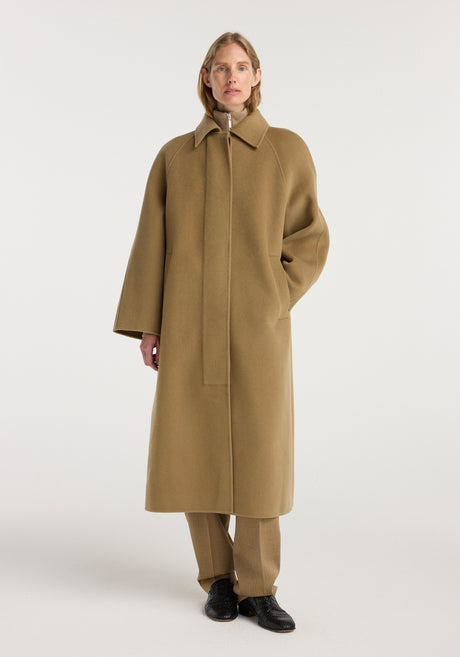 A model wearing a long camel-colored Double-faced wool padded coat | camel with a classic collar and concealed front closure, styled with matching pants and black shoes.