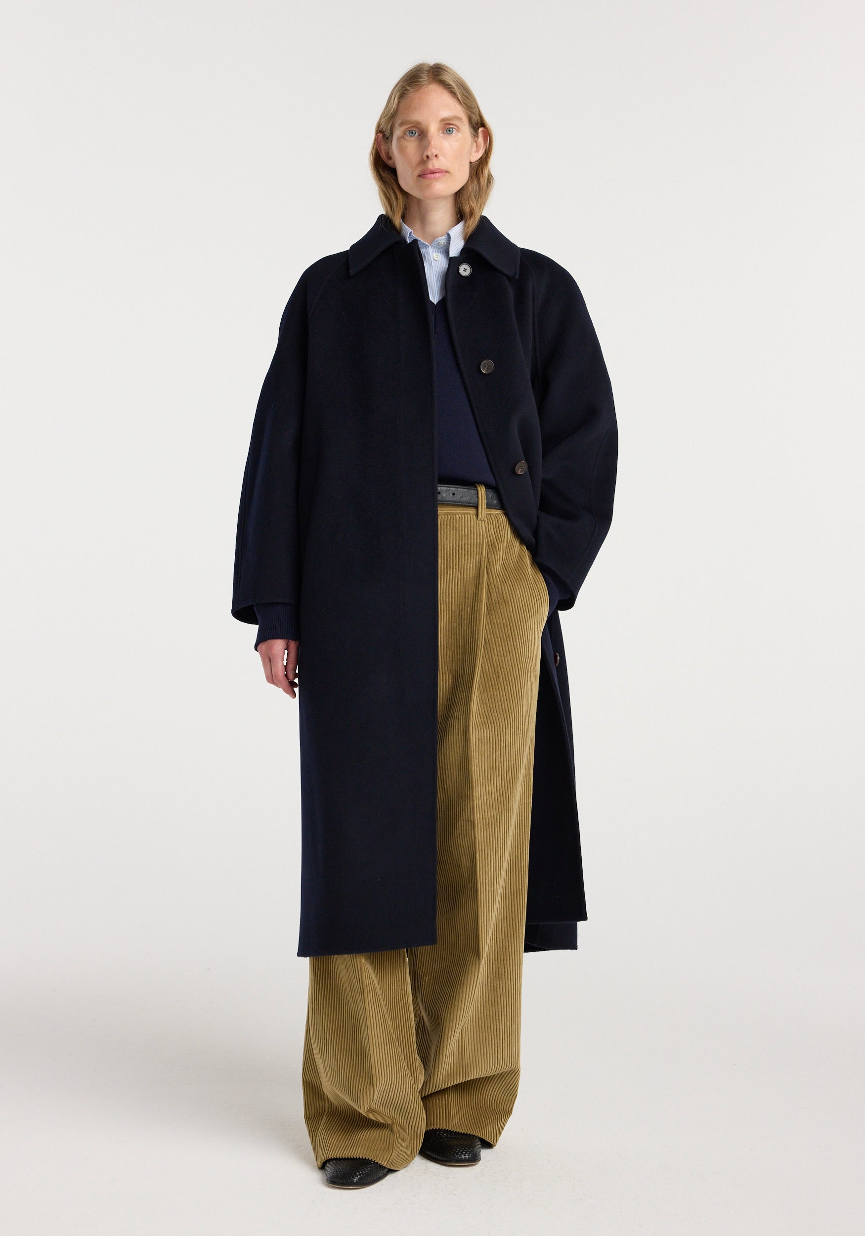 Woman wearing a navy double-faced wool padded coat buttoned in front, paired with a navy sweater, light blue shirt, and wide-legged beige corduroy pants against a neutral background, showcasing the Double-faced wool padded coat | navy.