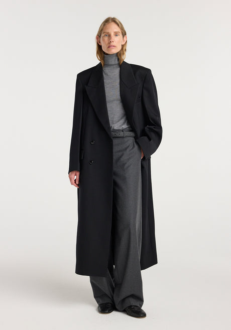 Model wearing a black double breasted tailored coat over a gray turtleneck and wide-leg trousers, showcasing a sleek and sophisticated outfit with the Double breasted tailored coat | black.